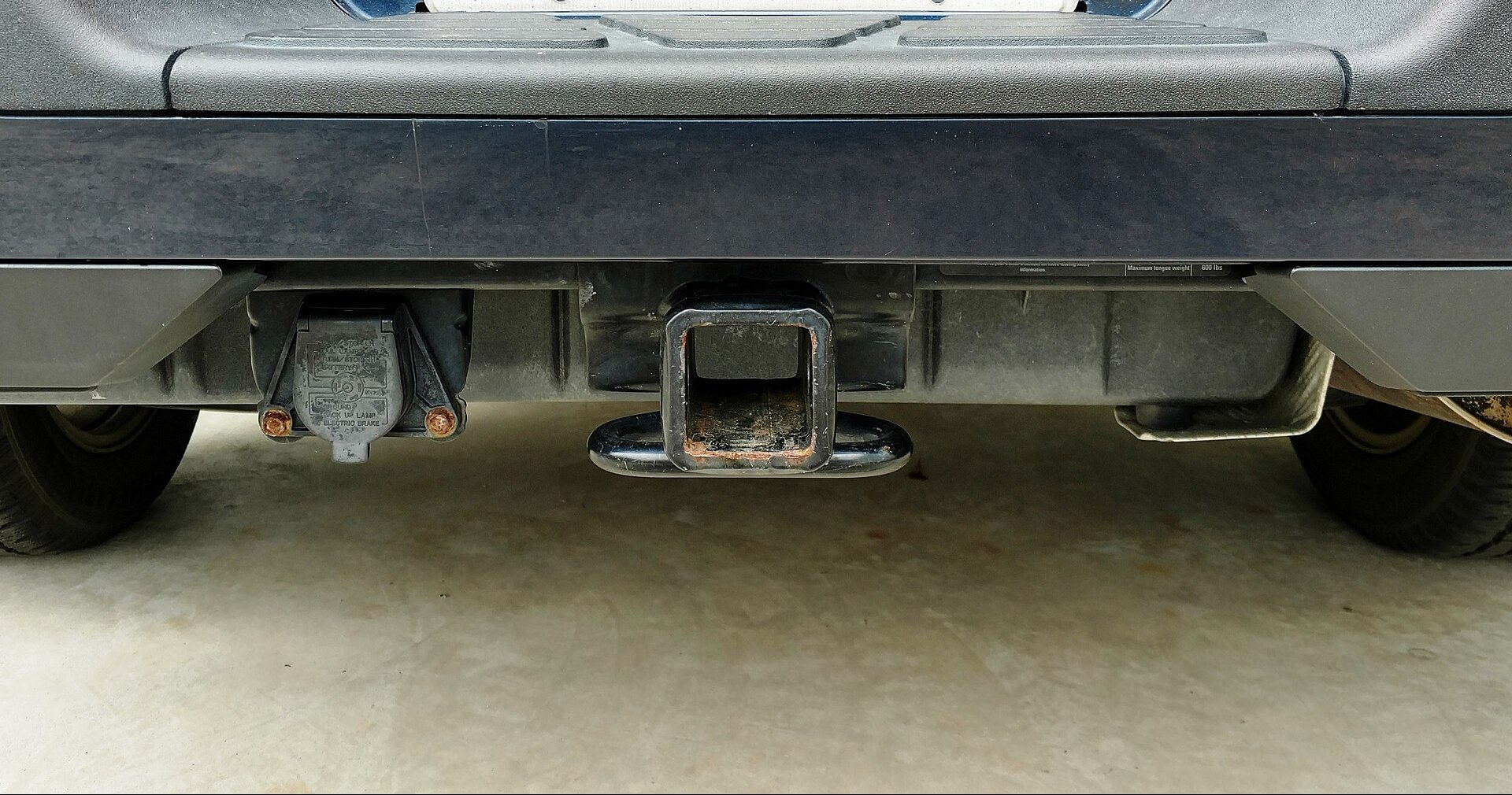 PLACEHOLDER: a class three receiver hitch and a seven pin electrical plug under the rear bumper of a pickup.